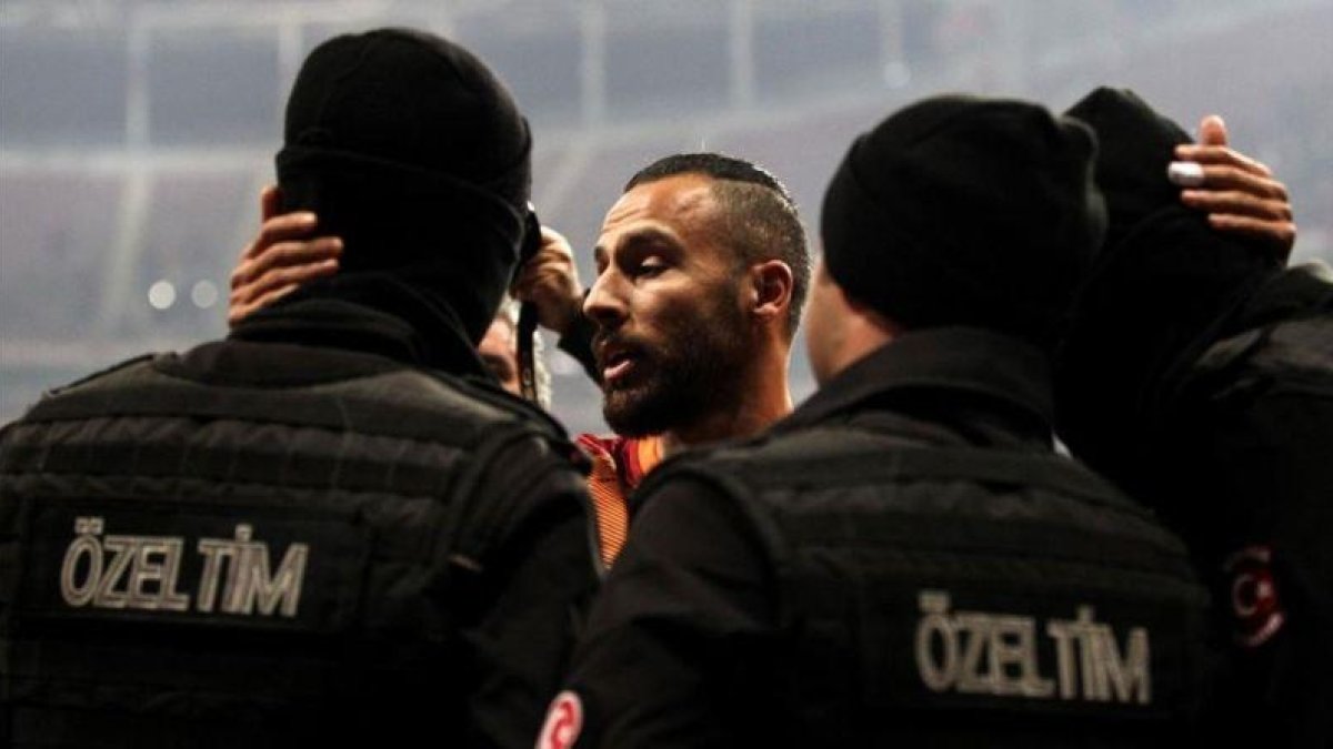 Yasin Oztekin se abraza a dos policías en el estadio del Galatasaray.-AFP