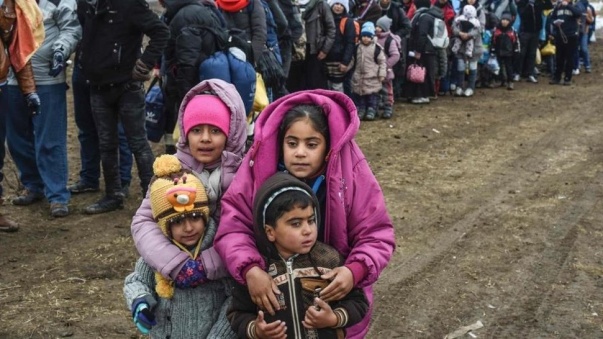 Unos niños sirios esperan junto a otros refugiados para cruzar la frontera entre Macedonia y Serbia.-/ AFP / ARMEND NIMANI