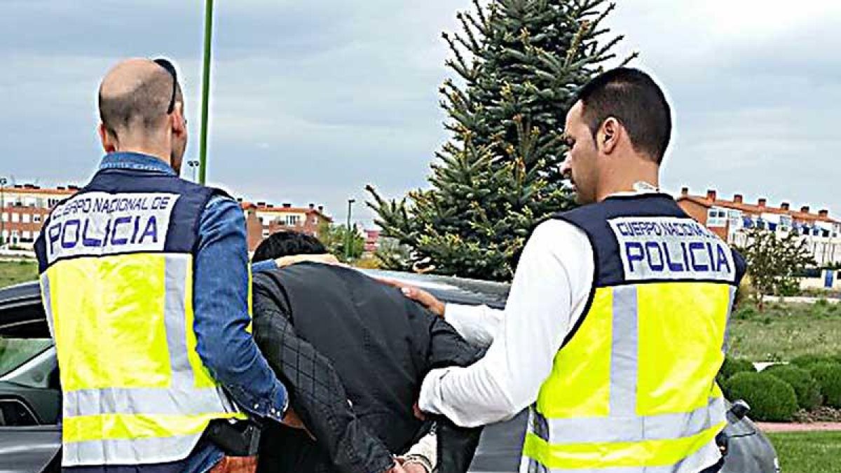 Dos agentes introducen a uno de los detenidos en un coche.-ECB