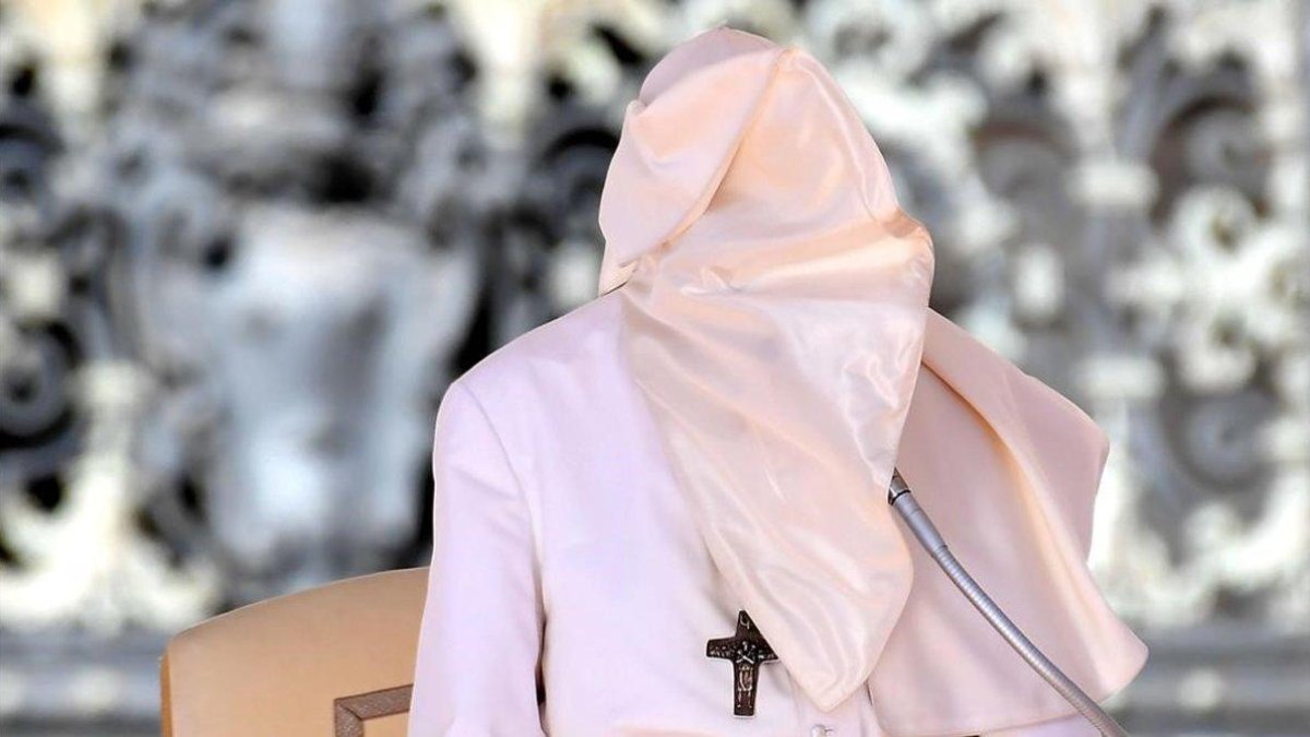 El Papa, con la cara tapada con el hábito a causa del fuerte viento que soplaba durante su intervención semanal ante los fieles en la plaza de San Pedro, en el Vaticano.-TIZINA FABI (AP)