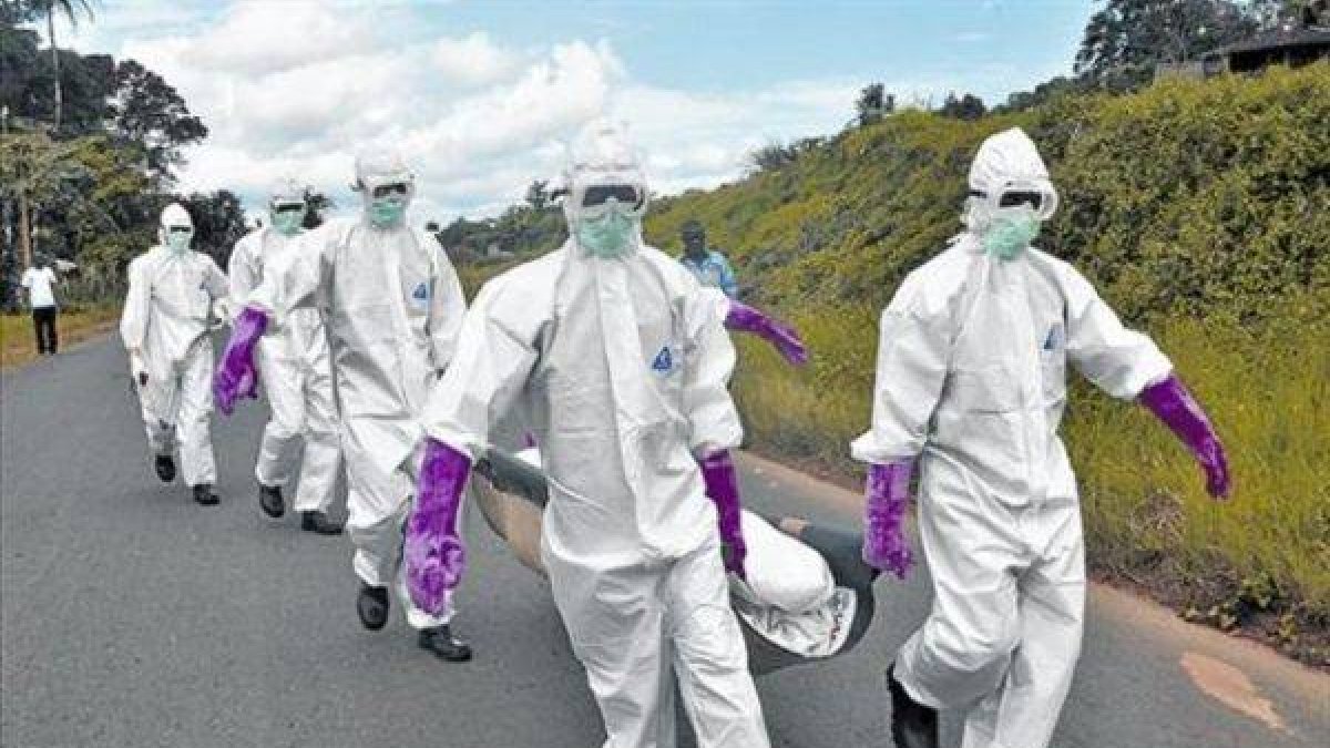 Personal protegido con trajes especiales retira el cuerpo de un fallecido por ébola en Monrovia (Liberia).-Foto:   AP / ABBAS DULLEH