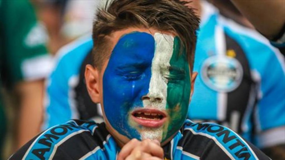 Un aficionado del Gremio llora durante el homenaje al Chapecoense.-AFP / JEFFERSON BERNARDES