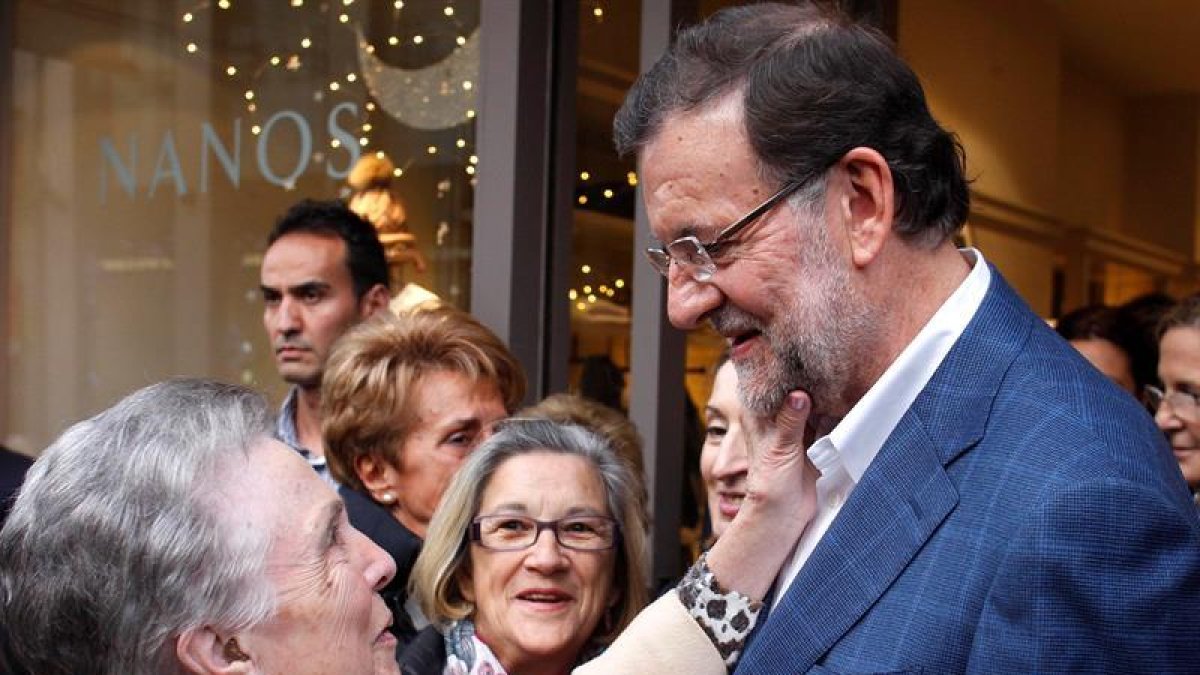 El presidente del Gobierno y candidato a la reelección por el PP, Mariano Rajoy, saluda a una mujer durante el recorrido que ha hecho hoy por las calles de Vigo, dentro de la campaña para las elecciones generales del 20D.-EFE