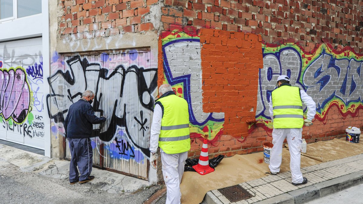 La cuadrilla de pintadas limpia unos bajos en la calle Santa Clara de la capital burgalesa. ISRAEL L. MURILLO