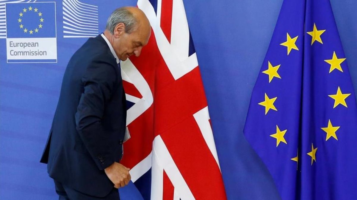 Un funcionario coloca las banderas de la UE y el Reino Unido al inicio de las negociaciones del brexit, el 19 de junio, en Bruselas.-REUTERS / FRANÇOIS LENOIR