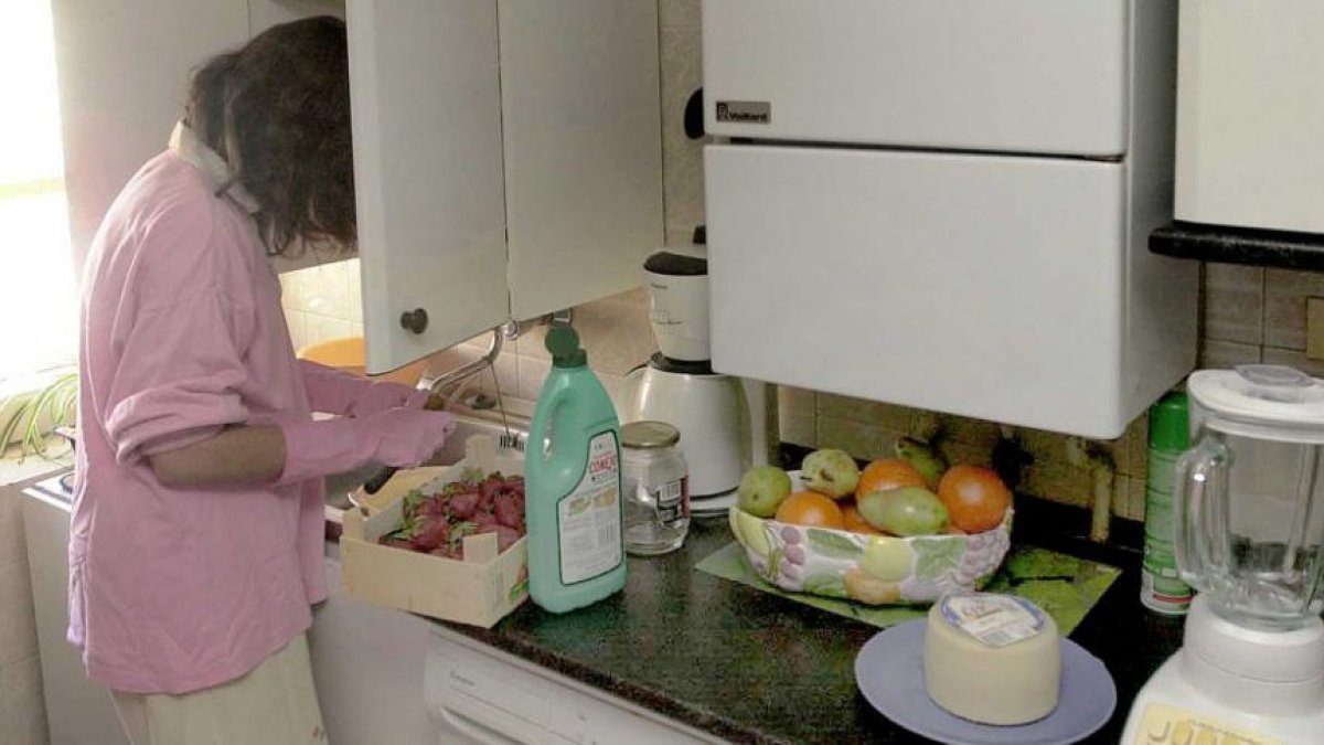 Una chica limpia una caja de fresas en su casa.-ISRAEL L. MURILLO