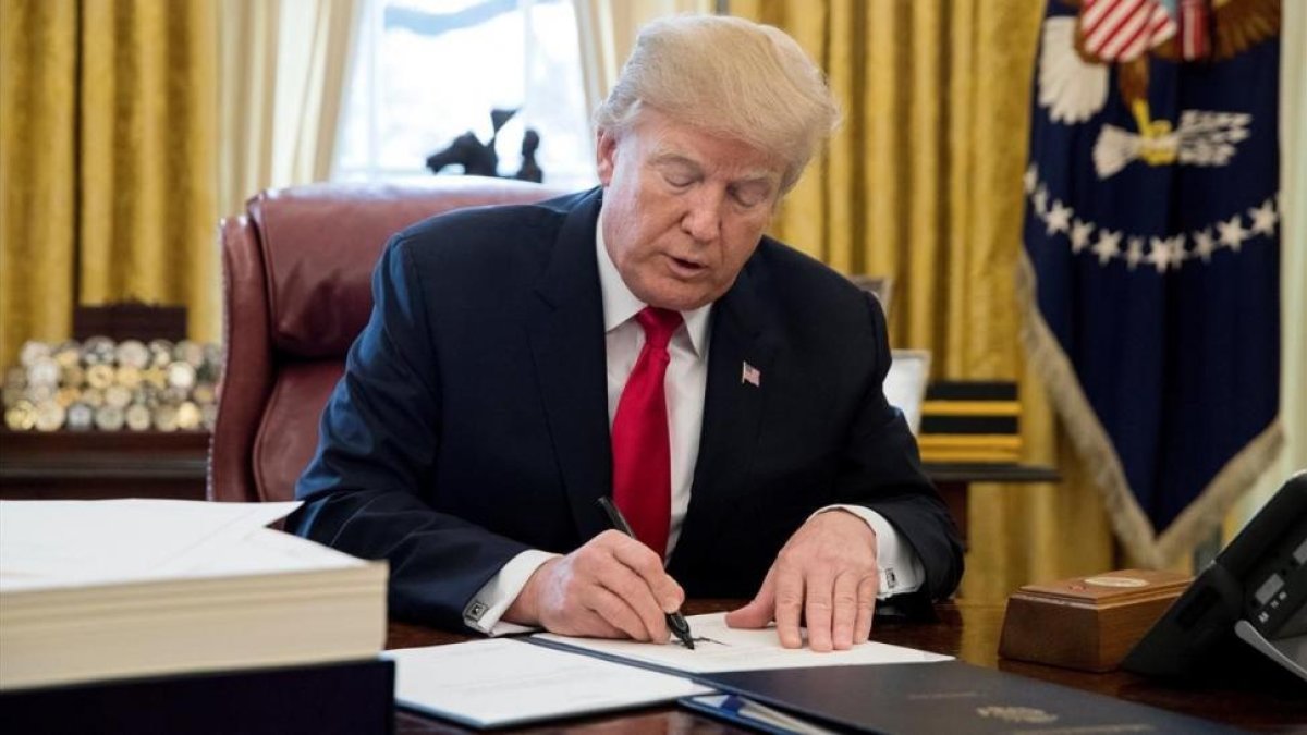 Trump firma la ley sobre la reforma fiscal, en el Despacho Oval de la Casa Blanca, en Washington, el 22 de diciembre.-/ EFE / MICHAEL REYNOLDS