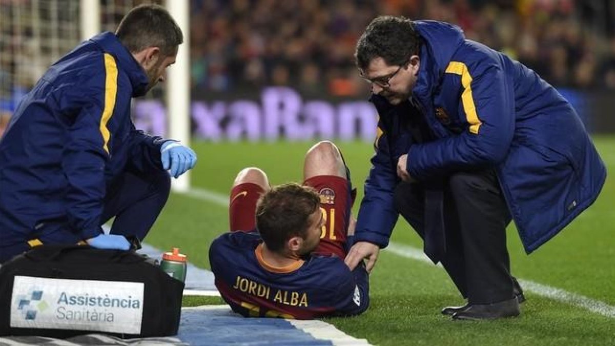 Jordi Alba es atendido tras su lesión muscular por el doctor Ricard Pruna (derecha).-AFP / LLUIS GENE