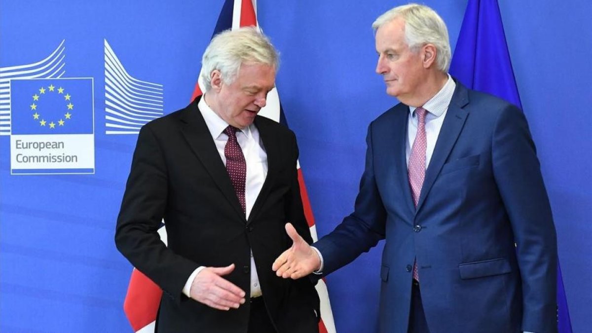 Michel Barnier tiende la mano a David Davis en la sede de la Comisión Europea, en Bruselas.-/ AFP / EMMANUEL DUNAND
