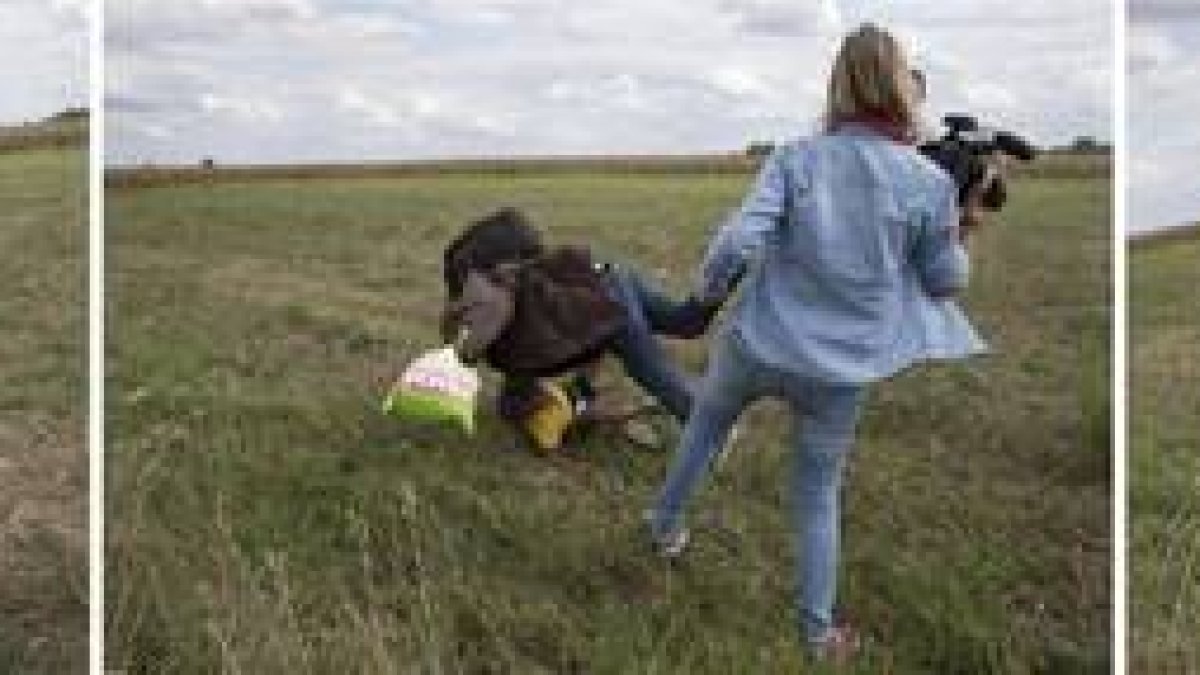 Petra Laszlo le hace la zancadilla a un padre que lleva en brazos a su hijo y una bolsa con sus pertenencias, en Roszke (Hungría).-MARKO DJURICA / REUTERS