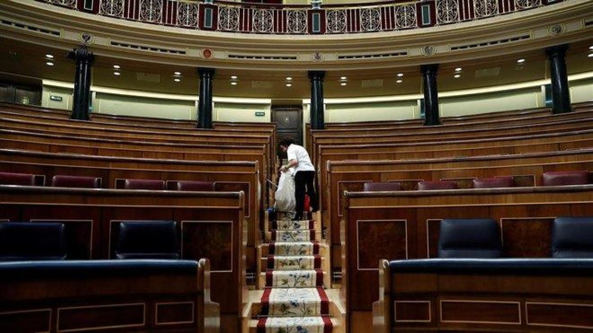Labores de limpieza en el hemiciclo del Congreso de los Diputados, tras quedarse vacío el pasado 28 de febrero.-EFE / CHEMA MOYA