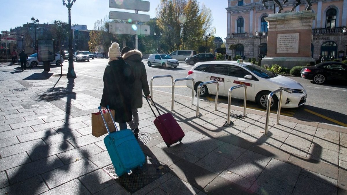 Una pareja de turistas camina por la plaza de Mío Cid, en Burgos, con sus maletas. TOMÁS ALONSO