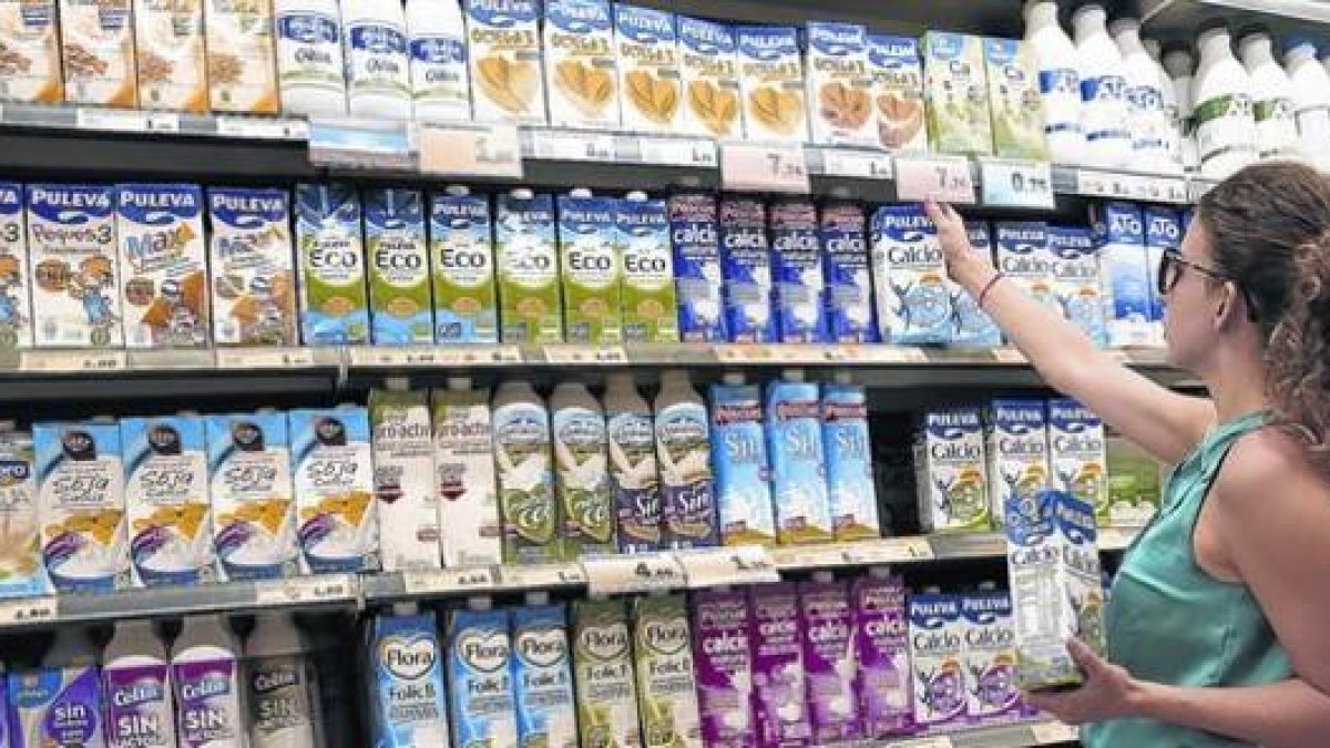 Una clienta elige leche entre la gran variedad de oferta del supermercado.-RICARD CUGAT