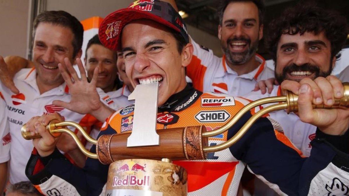 Marc Márquez muerde a lo Rafa Nadal el trofeo del GP de EUU, que ha ganado siempre.-REPSOL MEDIA / JAIME OLIVARES