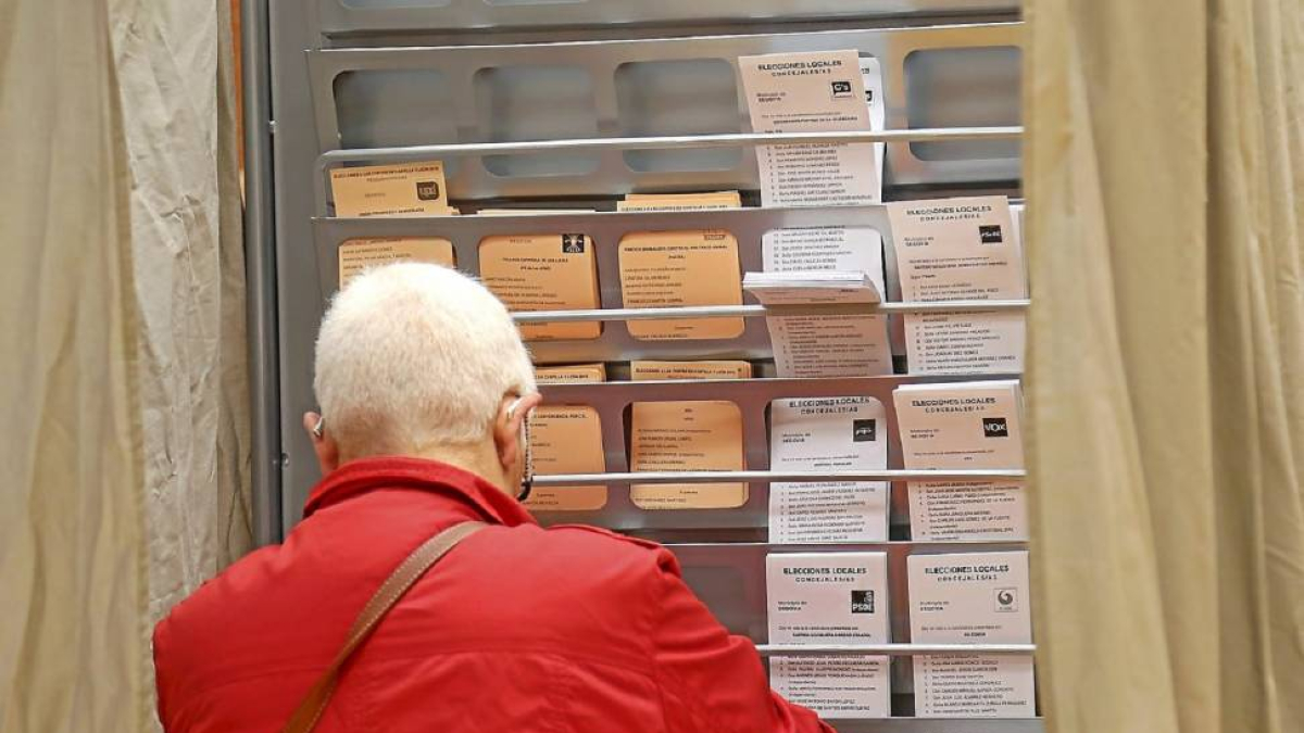 Una mujer busca la papeleta en un colegio electoral.