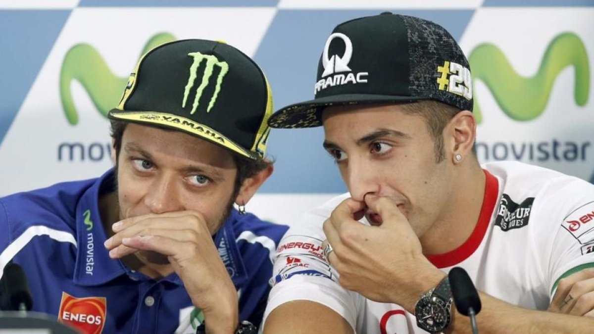 Andrea Iannone, a la derecha, dialoga con Valentino Rossi.-EFE / ANDREU DALMAU