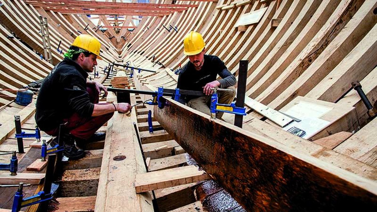 Dos operarios trabajan en la reconstrucción de la Nao de San Juan, promovida por el colectivo Albaola en Pasajes (Guipúzcoa).-ALBAOLA
