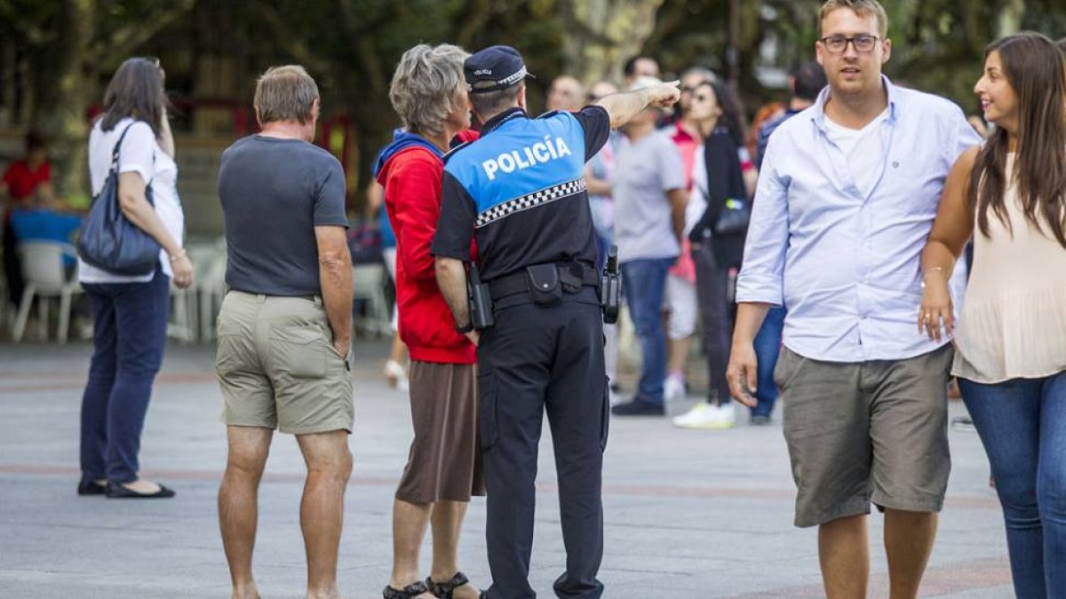Un agente de la Policía Local realiza unas indicaciones a dos personas.-SANTI OTERO