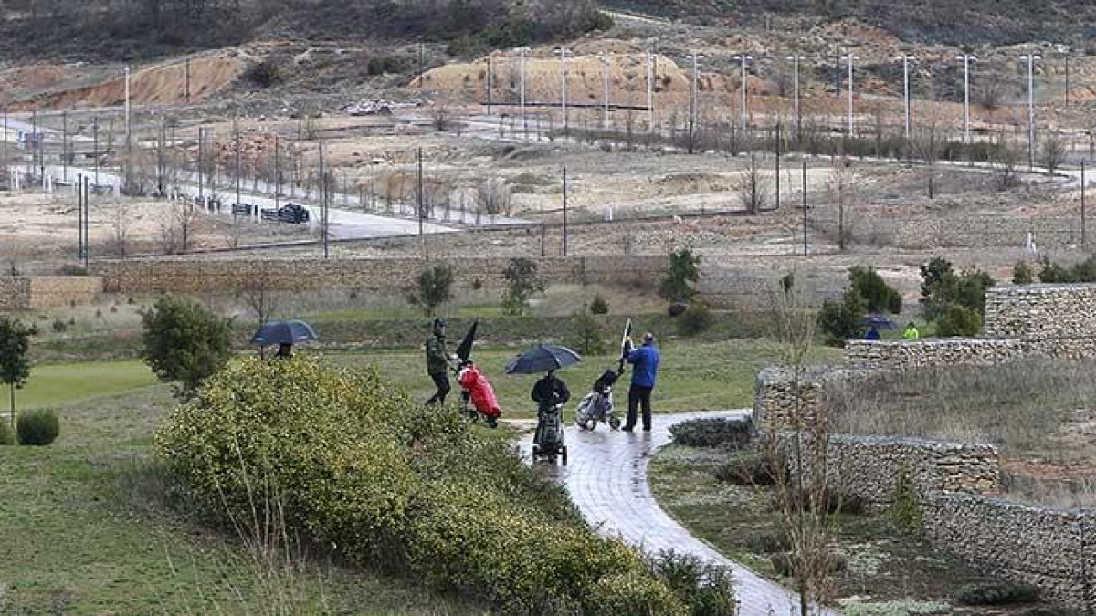 Varios jugadores practicando ayer el golf en el campo de Saldaña. De fondo se aprecia la urbanización de las parcelas de este sector, que está aún sin pagar y por rematar.-RAÚL OCHOA