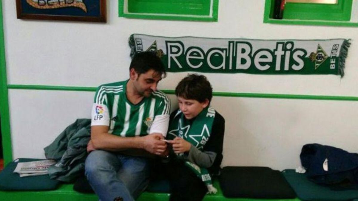 El pequeño Pere Ribas junto a Diego Sánchez, miembro de la Peña Bética de Girona-Olot.-EL PERIÓDICO