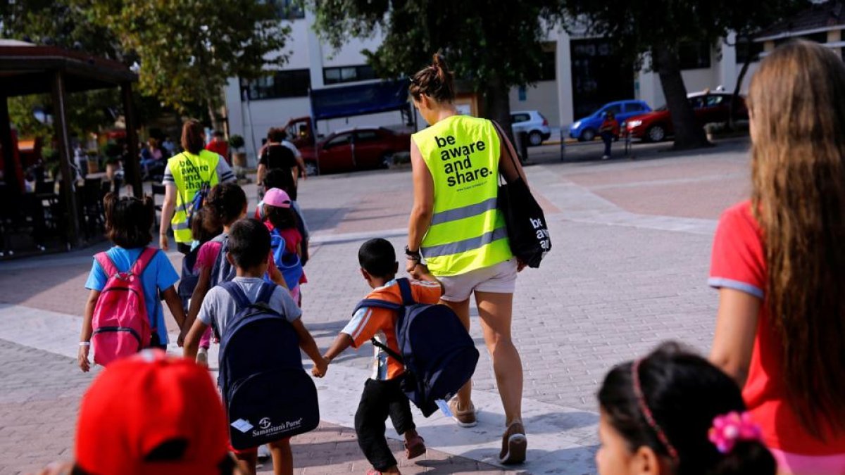 Unos voluntarios acompañan a la escuela a niños refugiados en la isla griega de Chios.-ALKIS KONSTANTINIDIS / REUTERS