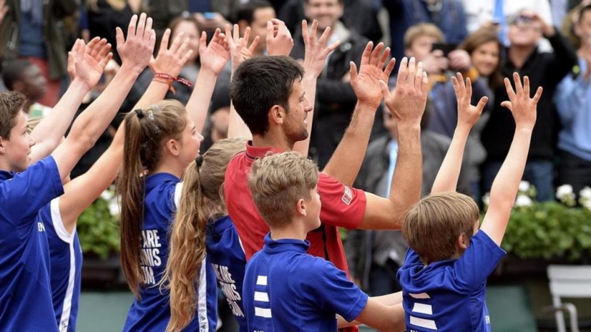 Djokovic celebra con los recogepelotas su victoria en París.-ETIENNE LAURENT