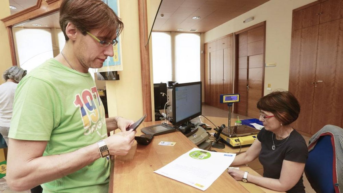 Un hombre adquiere una pegatina en la sede de Correos.-RAÚL G. OCHOA
