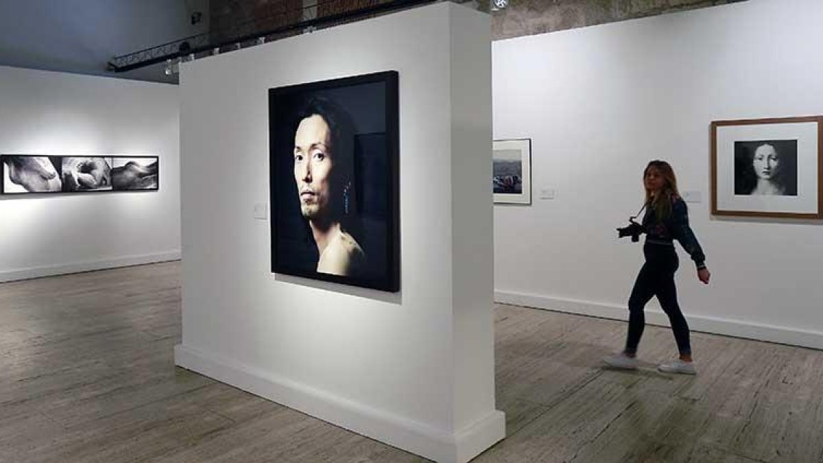 Una fotógrafa pasa por una sala en la que domina el retrato de Pierre Gonnord junto a obras de Castro Prieto (d.) o Enrique Carrazoni (i.).-Raúl Ochoa