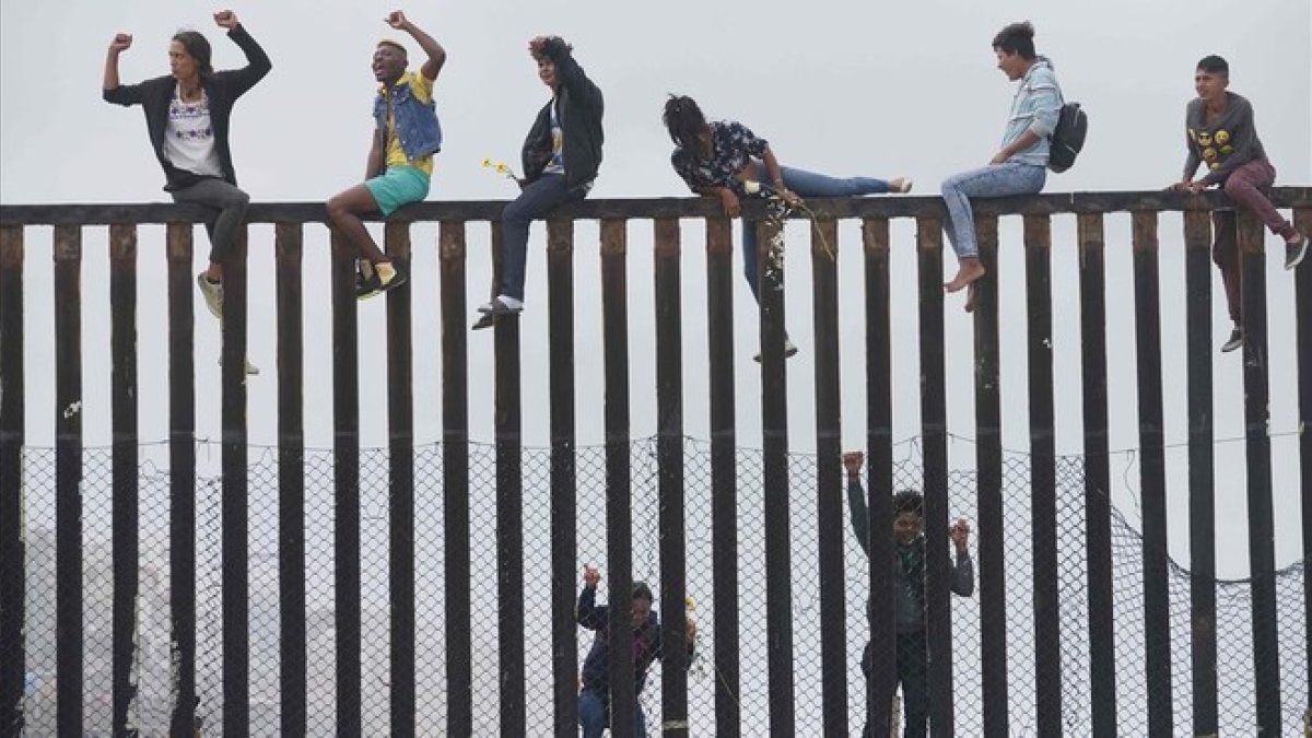 Miembros de la caravana de migrantes que cruzó México a pie hasta la frontera con Estados Unidos trepan el muro fronterizo que separa ambos países el pasado 29 de abril del 2018.-SANDY HUFFAKER (AFP)