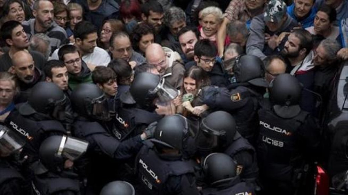 Agentes de la Policía Nacional intentan desalojar a las personas concentradas en las puertas del colegio Ramón Llull de Barcelona el 1-O.-FERRAN NADEU