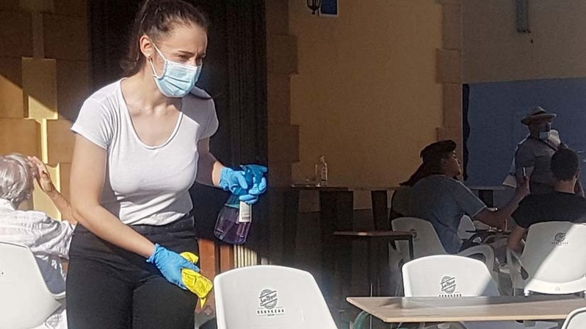 Una camarera limpia y desinfecta una mesa en un bar de Aranda. L. V.
