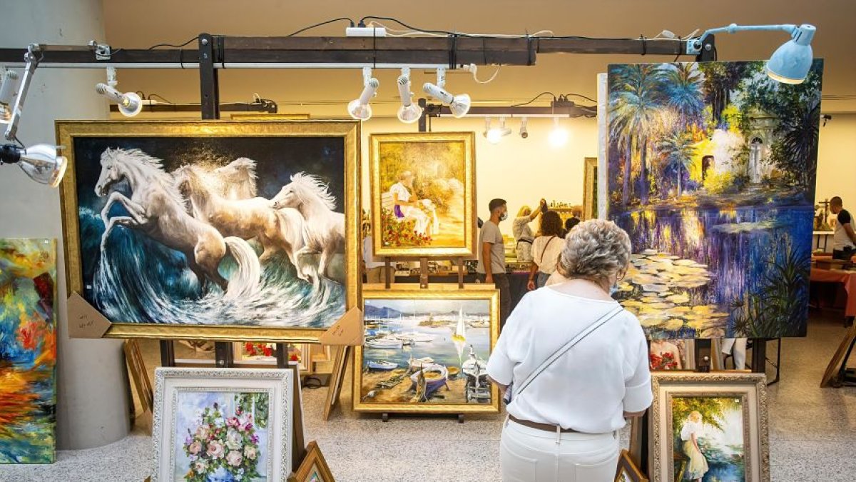 Una de las visitantes contempla varios cuadros de diferentes temáticas y tamaños expuestos en la feria de antigüedades y coleccionismo. FOTOS: SANTI OTERO