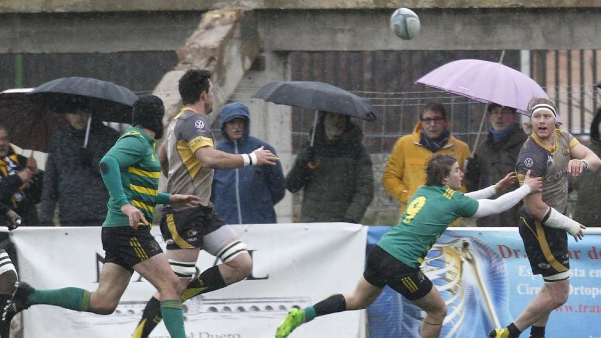 Imagen de un partido en San Amaro con los aficionados siguiendo el juego de pie y refugiados bajo los paraguas.-SANTI OTERO
