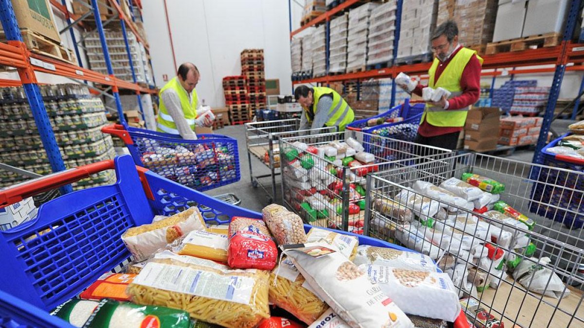 Tres voluntarios del Banco de Alimentos de Burgos gestionan el reparto de alimentos en el almacén de la entidad.-ISRAEL L. MURILLO