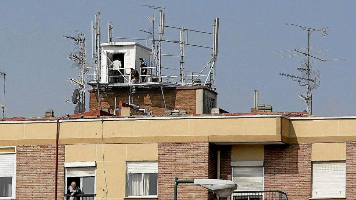 Dos técnicos revisan la instalación de las antenas de un edificio.-LOSTAU