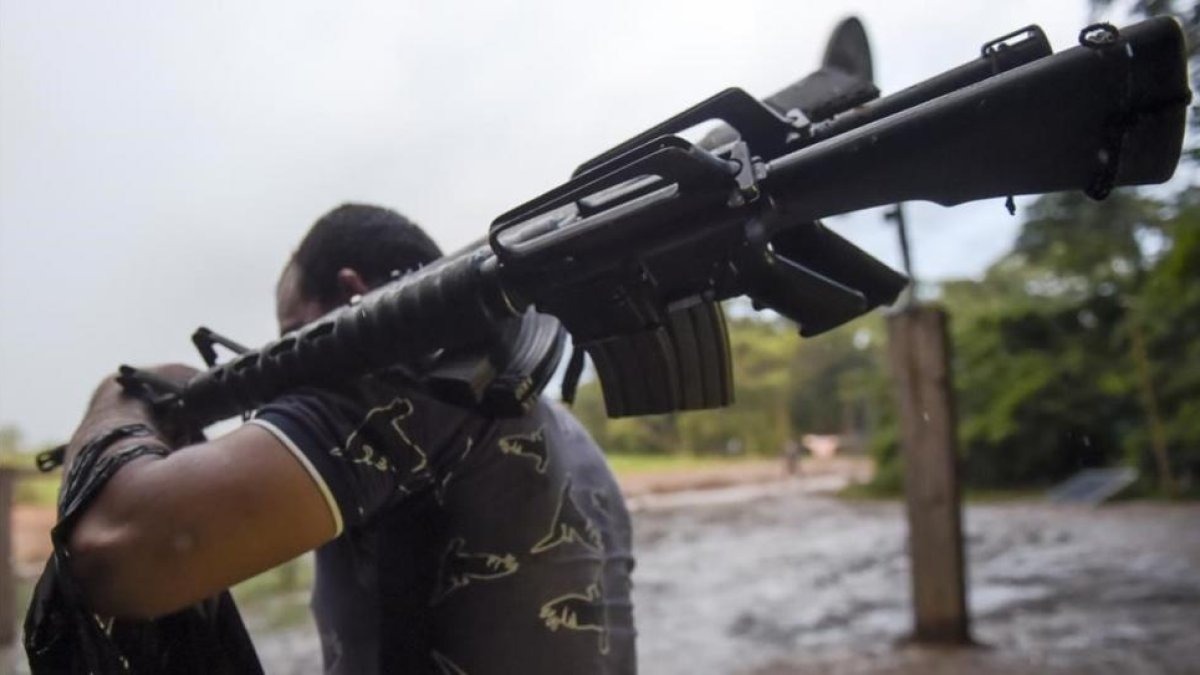Un miembro de las FARC entrega un fusil de asalto.-AFP