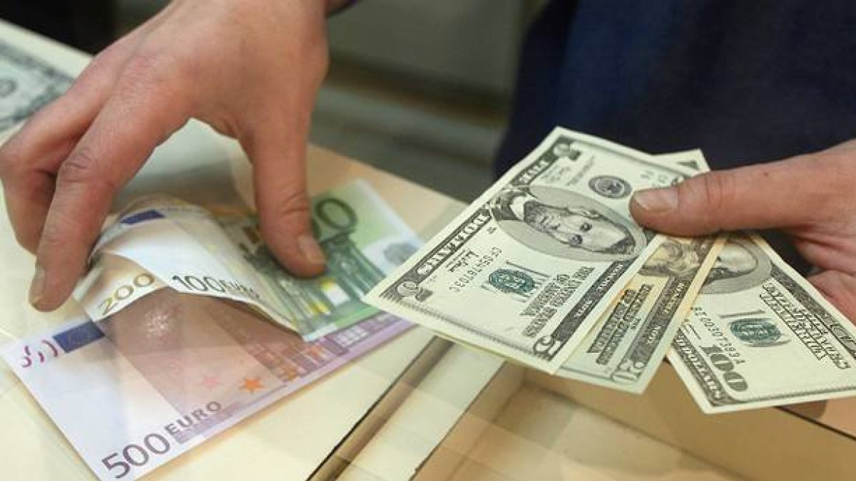 Euros y dólares en las manos.-Foto: ARCHIVO/ AFP