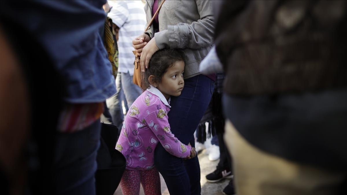Una niña mexicana con su madre espera con otros inmigrantes en la frontera la respuesta a la solicitud de asilo político en EEUU.-GREGORY BULL (AP)