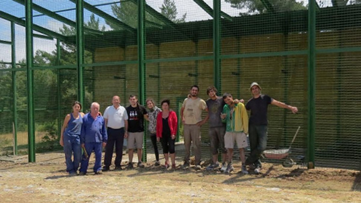 Un grupo de voluntarios ante la jaula construida en Huerta de Arriba para la reintroducción del buitre negro.-GREFA