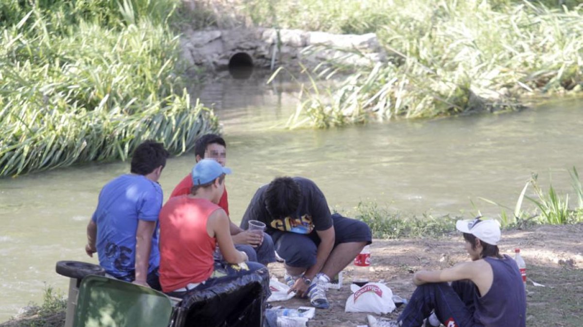 Un grupo de jóvenes hace botellón en la orilla del río.-ISRAEL L. MURILLO