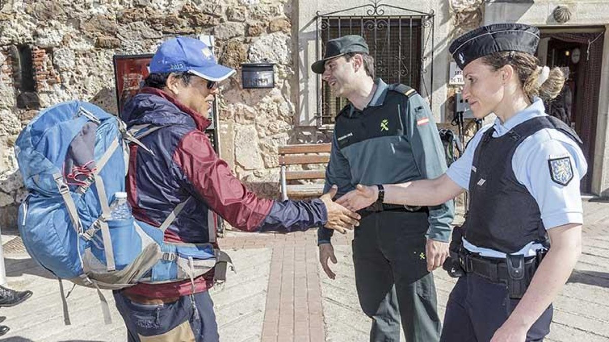 La gendarme Sofía Mateos y un agente de la Guardia Civil saludan a un peregrino en San Juan de Ortega.-SANTI OTERO