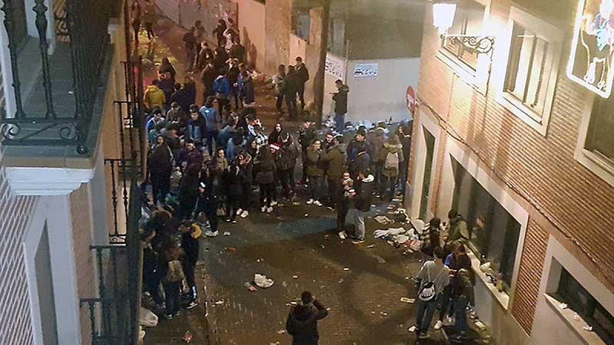 Un numeroso grupo de jóvenes concentrados en la calle donde son evidentes los restos de un botellón.-