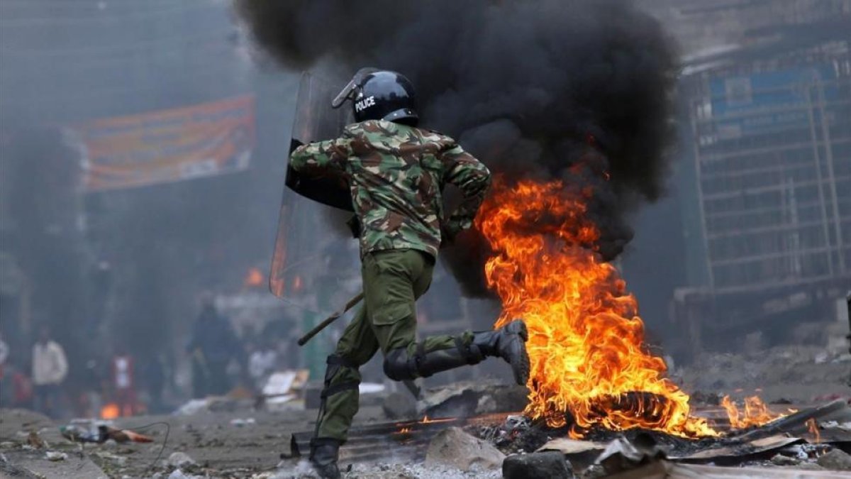 Un agente antidisturbios salta una barricada en llamas levantada por seguidores del opositor Raila Odinga, en Mathare (Nairobi), el 12 de agosto.-REUTERS / THOMAS MUKOYA