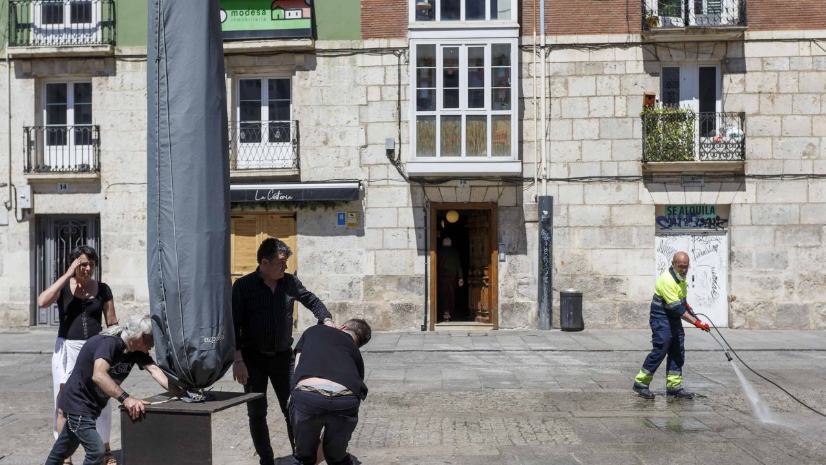 Varios trabajadores trasladan una sombrilla este martes en la plaza de La Flora. SANTI OTERO