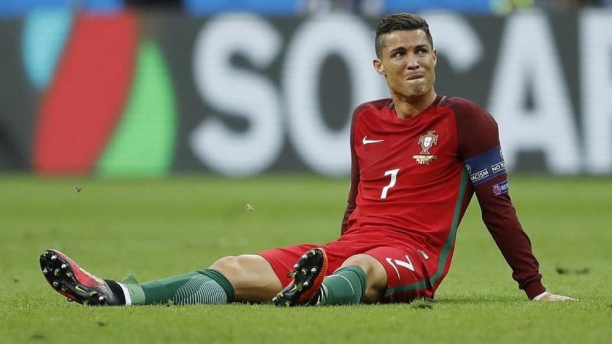 Cristiano, en el suelo después de sufrir el fuerte golpe en la rodilla que le hizo abandonar el campo.-AP / FRANK AUGSTEIN