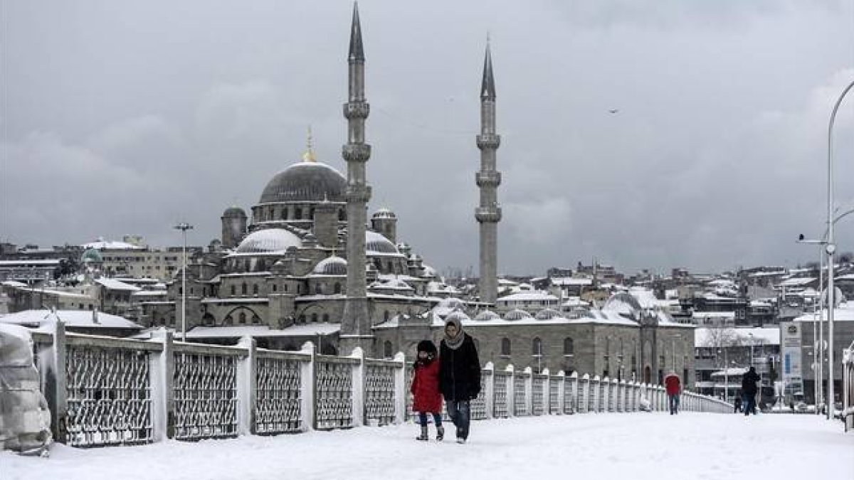 Varios transeúntes caminan por un nevado puente de Galata, en Estambul, este miércoles.-Foto: AFP / BULENT KILIC