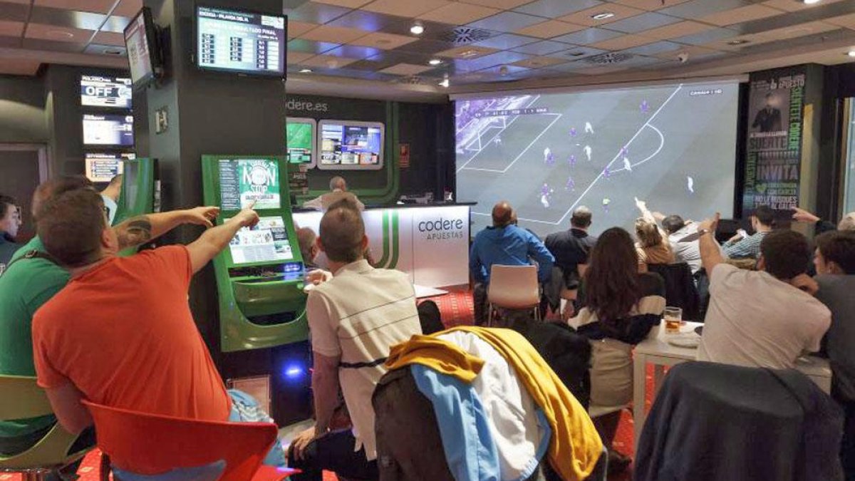 Varios jóvenes en una sala de apuestas deportivas.