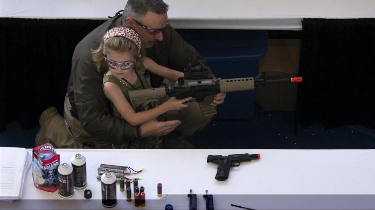 Un hombre muestra a una niña cómo coger una escopeta de aire comprimido durante el NRA Youth Day, en la reunión anual de la NRA, en Houston, en el 2013.-/ REUTERS / ADREES LATIF