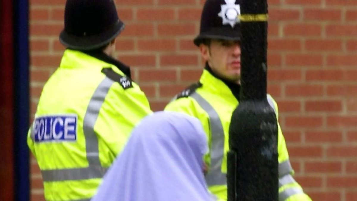 Una mujer musulmana pasa junto a dos policías británicos.-MAX NASH