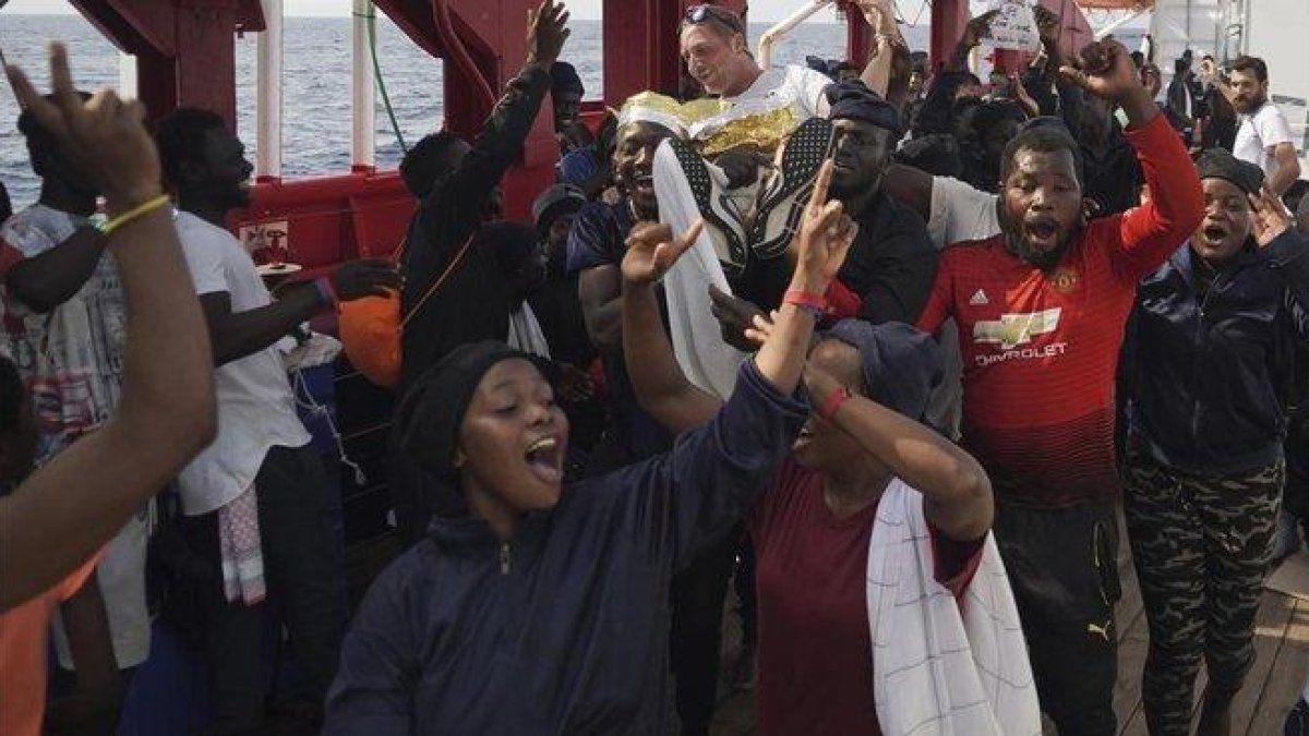 Los inmigrantes del ’Ocean Viking’ celebran que van a poder desembarcar este martes en Italia.-AP / RENATA BRITO